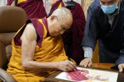 Его Святейшество Далай-лама подписывает свой портрет для Фонда премии Рамона Магсайсая, расположенного на Филиппинах. Дхарамсала, штат Химачал-Прадеш, Индия. 26 апреля 2023 г. Фото: Тензин Чойджор (офис ЕСДЛ).