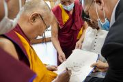 Его Святейшество Далай-лама подписывает свой портрет, нарисованный участником встречи с членами Молодежного буддийского общества Индии. Дхарамсала, штат Химачал-Прадеш, Индия. 13 июня 2023 г. Фото: дост. Тензин Джампхел (офис ЕСДЛ).